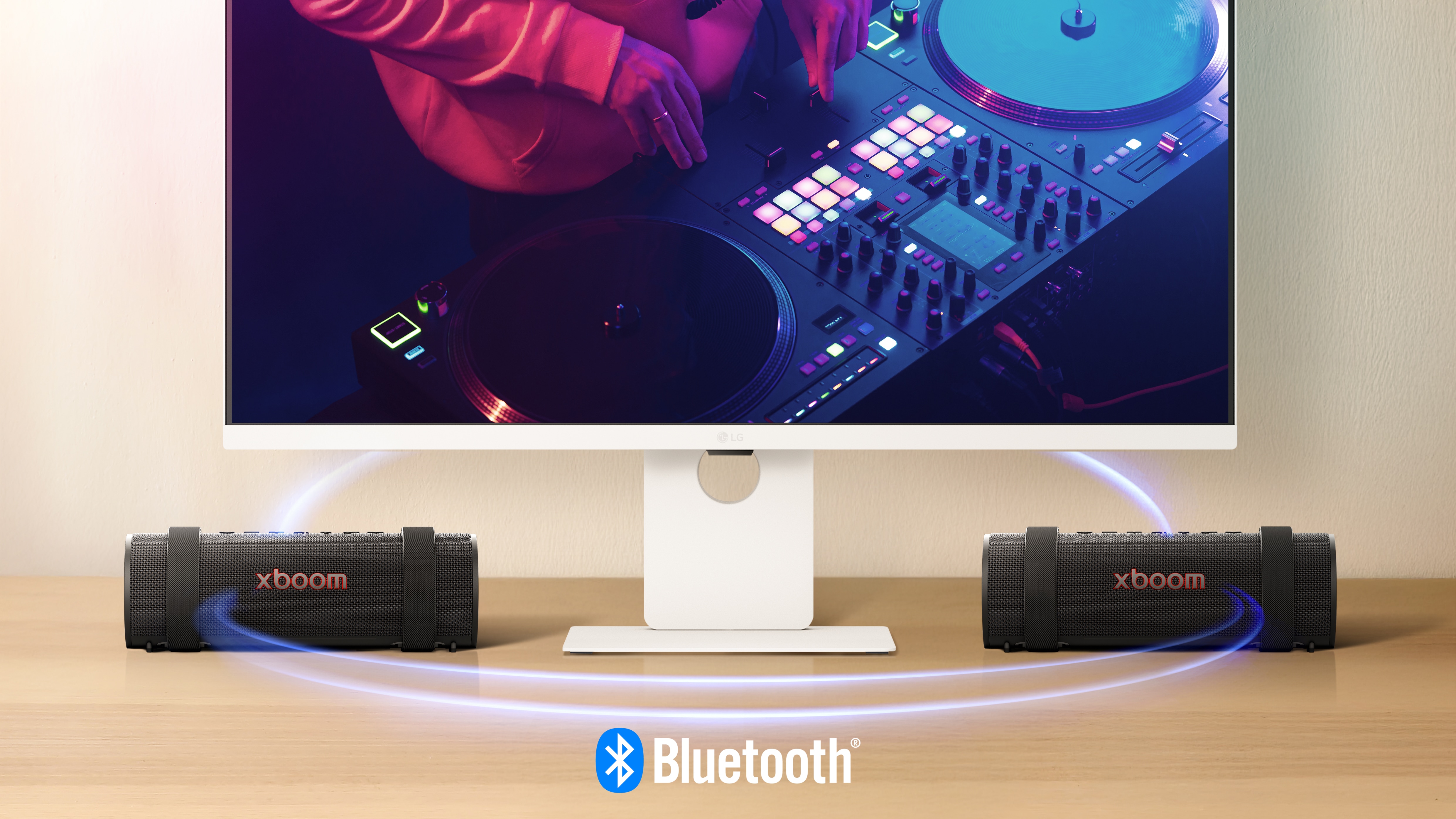 شاشة LG Smart Monitor تعرض مشهد دي جي، ويوجد على جانبيها سماعتان من XBOOM Grab. خط ضوئي أزرق افتراضي يربط الأجهزة الثلاثة ليُظهر أنها متصلة عبر البلوتوث.